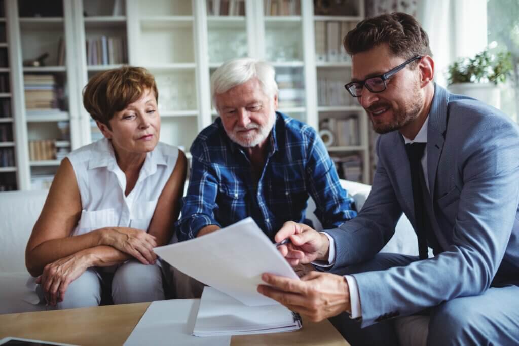 man reading a document to older couple, everyone looking pleased
